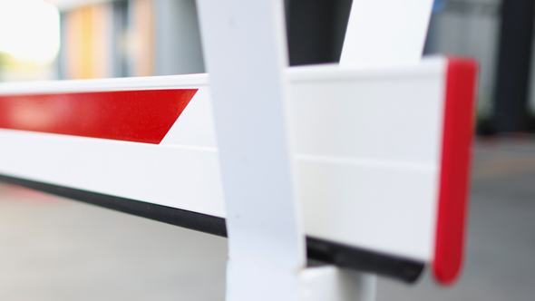 red and white entrance and exit barrier close up